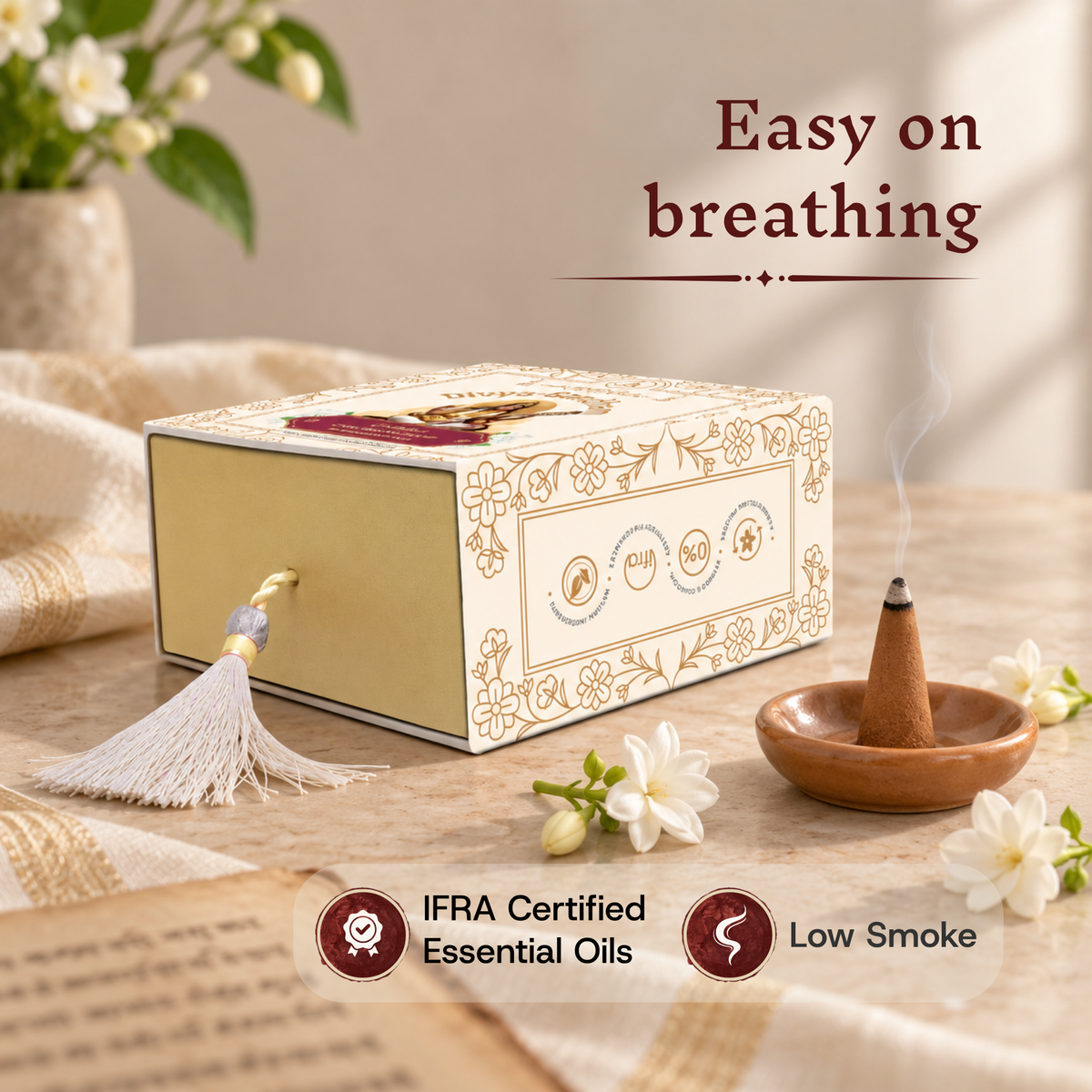 Lit Divyagandham Chameli incense cone highlighting easy breathing, IFRA certified essential oils, and low smoke, resting in front of the product box on a book.
