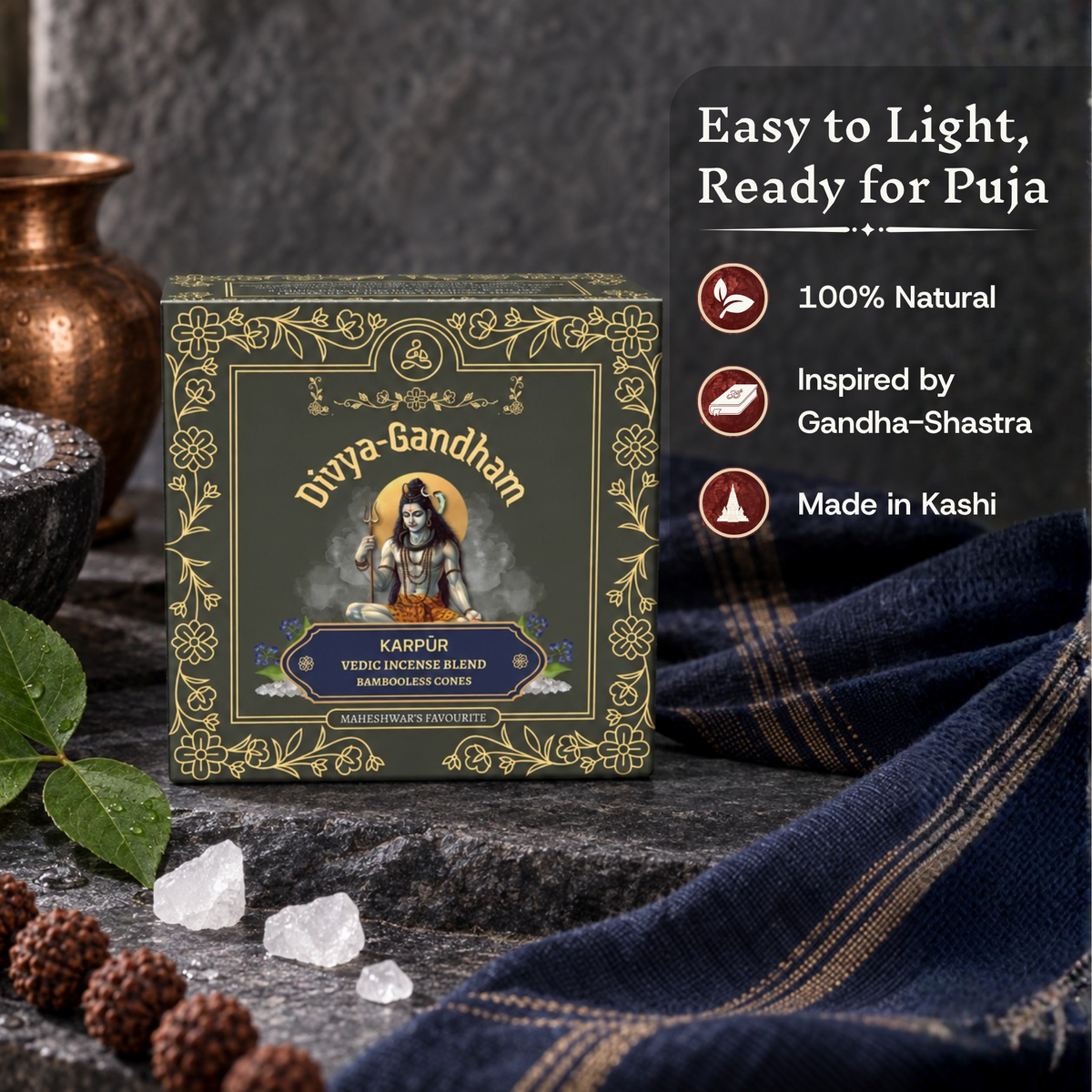 Upright Divyagandham Karpur incense cones box highlighting it is easy to light, 100% natural, inspired by Gandha-Shastra, and made in Kashi, placed on a dark stone near camphor and bel leaves.