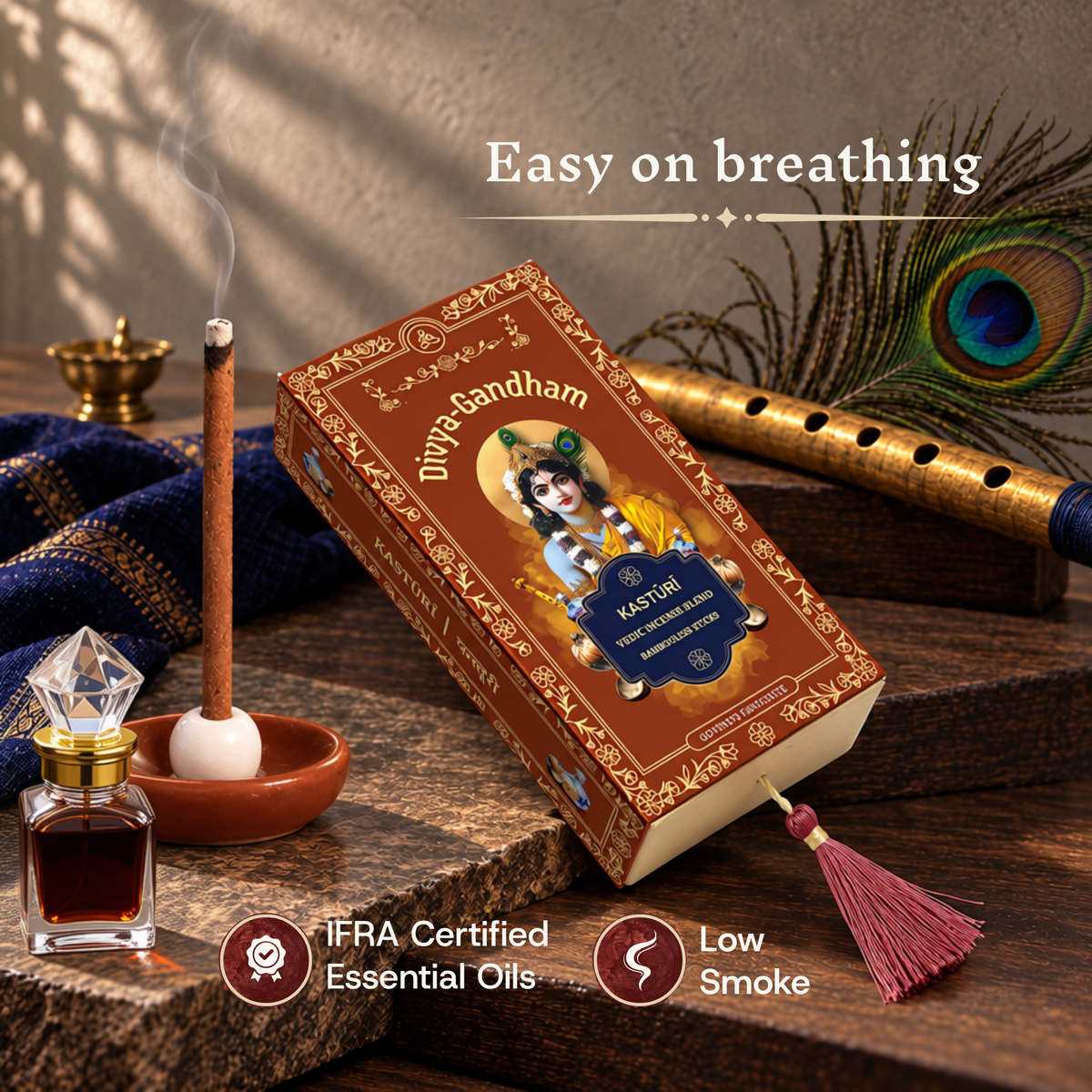 Lit Divyagandham Kasturi incense stick highlighting easy breathing, IFRA certified essential oils, and low smoke, resting near the product box, an attar bottle, and a flute.