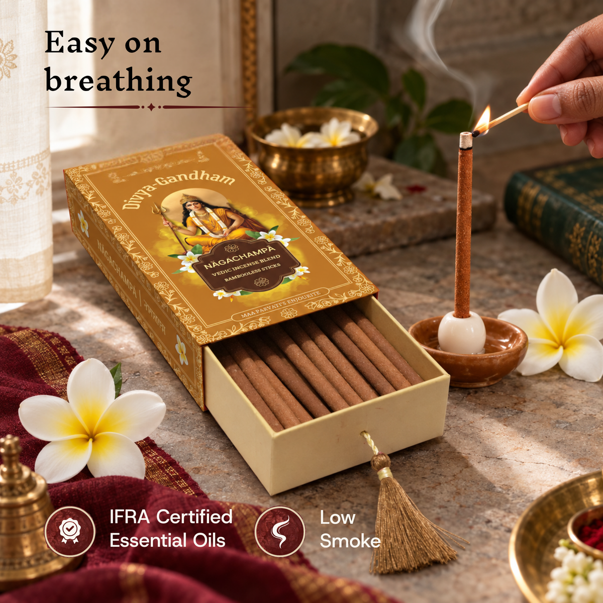 A hand lighting a Divyagandham Nagachampa incense stick from an open box, emphasizing easy breathing with IFRA certified essential oils and low smoke.