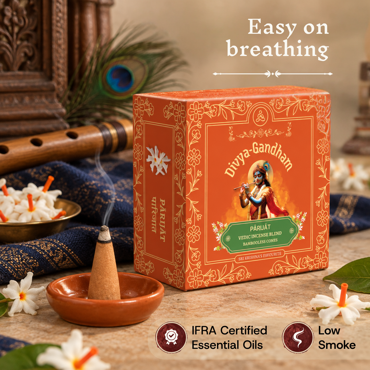 Lit Divyagandham Parijat incense cone highlighting easy breathing, IFRA certified essential oils, and low smoke, resting next to the product box on a blue patterned cloth.