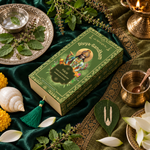 Overhead view of the Divyagandham Tulsi bambooless incense sticks box featuring Lord Vishnu, surrounded by fresh tulsi leaves, a conch shell, and a lit brass diya on a green cloth.